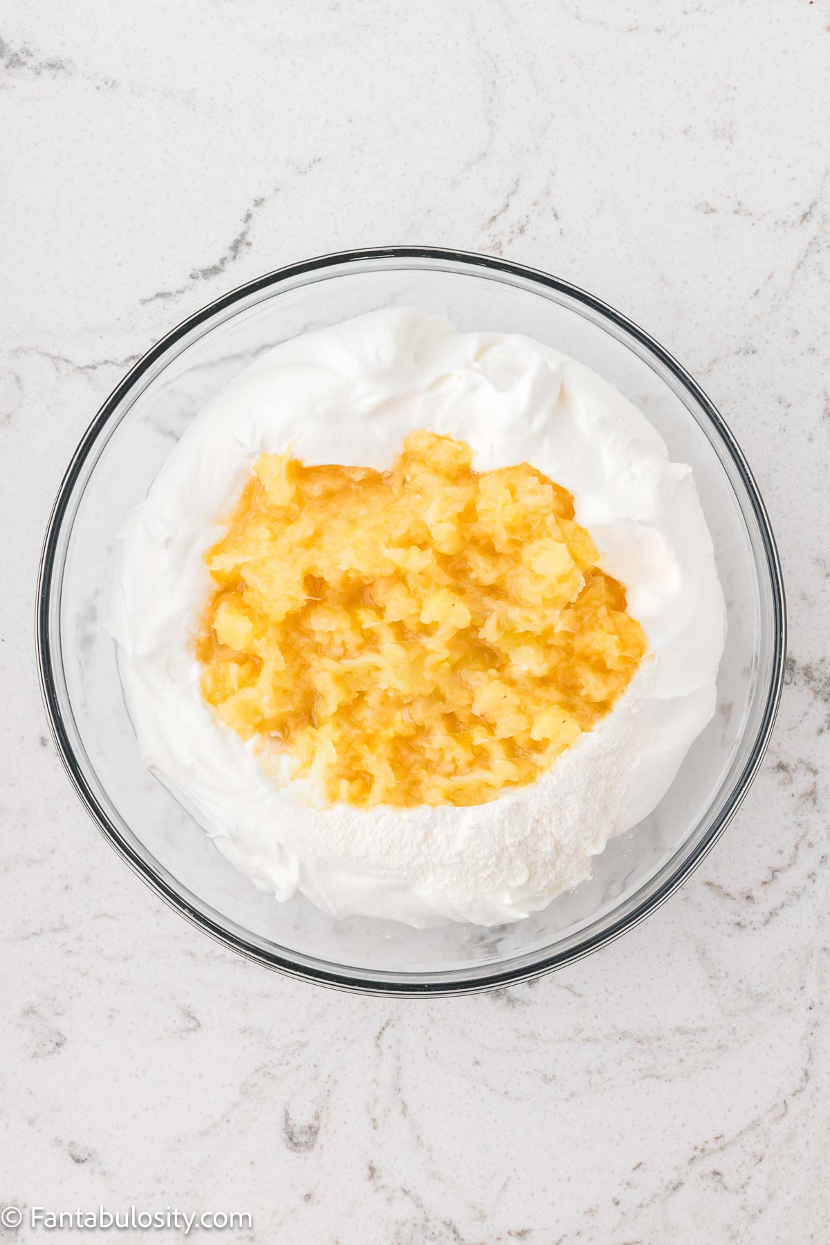 Crushed pineapple, pudding and Cool Whip in mixing bowl.