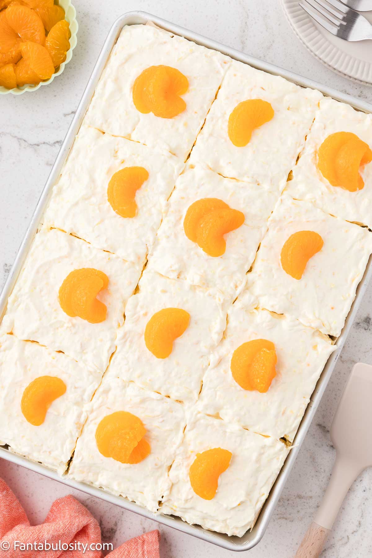 Mandarin orange slices placed on top of frosted pea pickin cake.