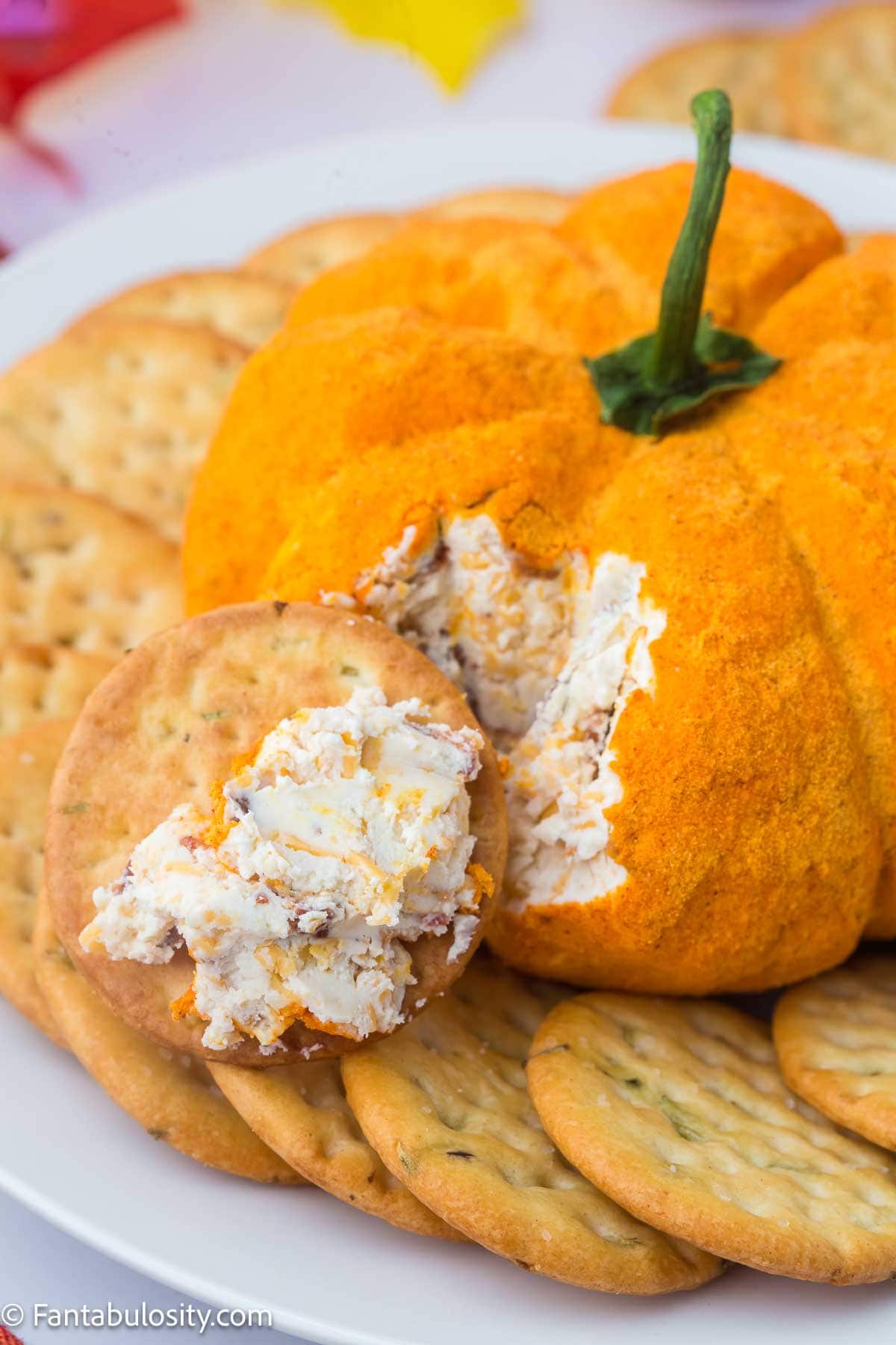 Pumpkin cheeseball with a bite taken out of it with a cracker.