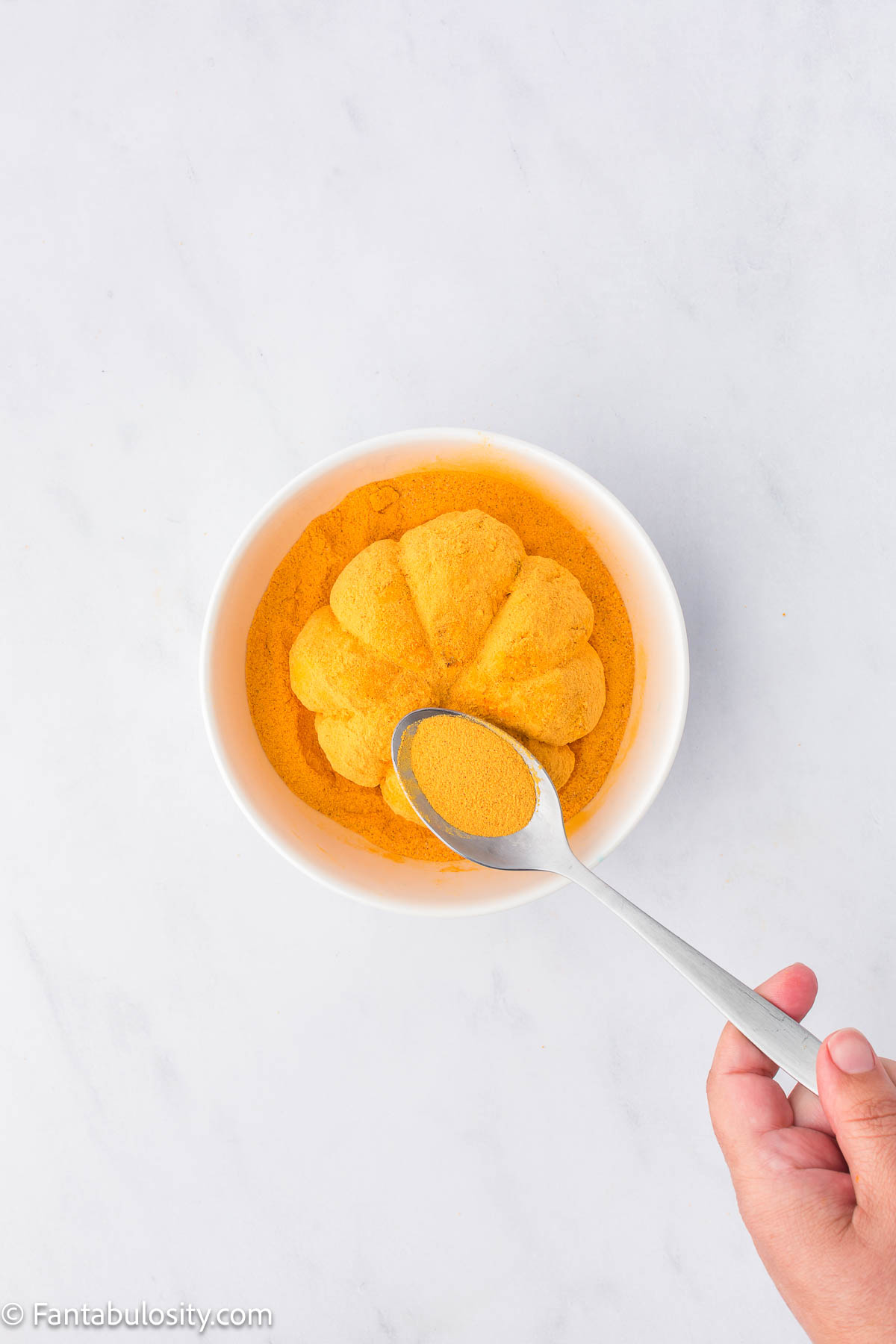 Cheeseball in bowl, sitting in cheddar cheese powder.