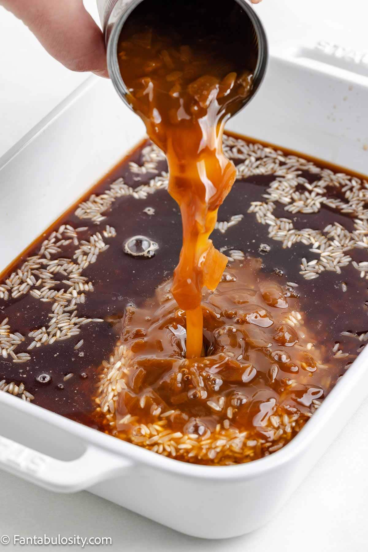 Rice, beef broth, and French onion soup poured in baking dish.