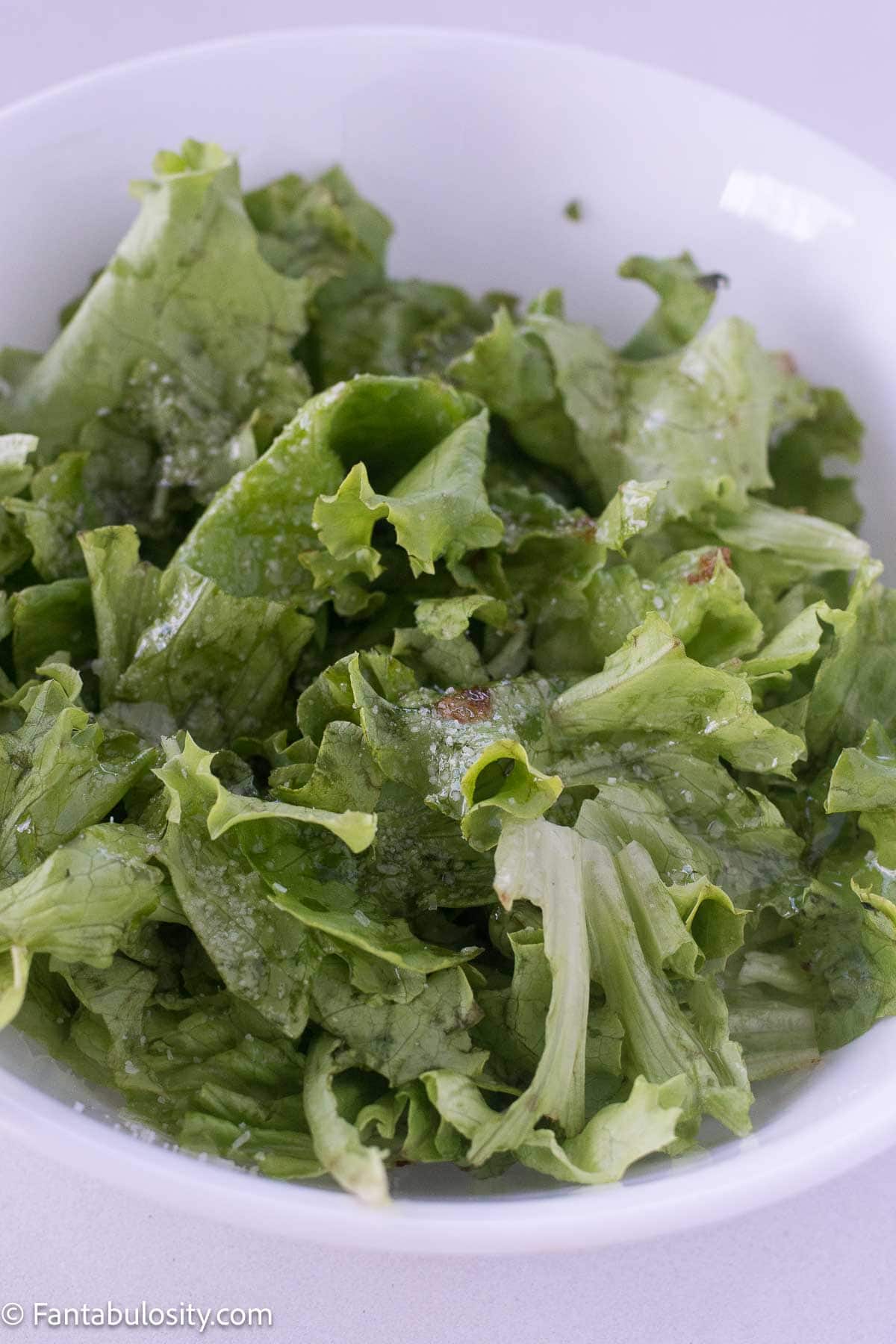 A bowl of lettuce with bacon grease dressing on top.