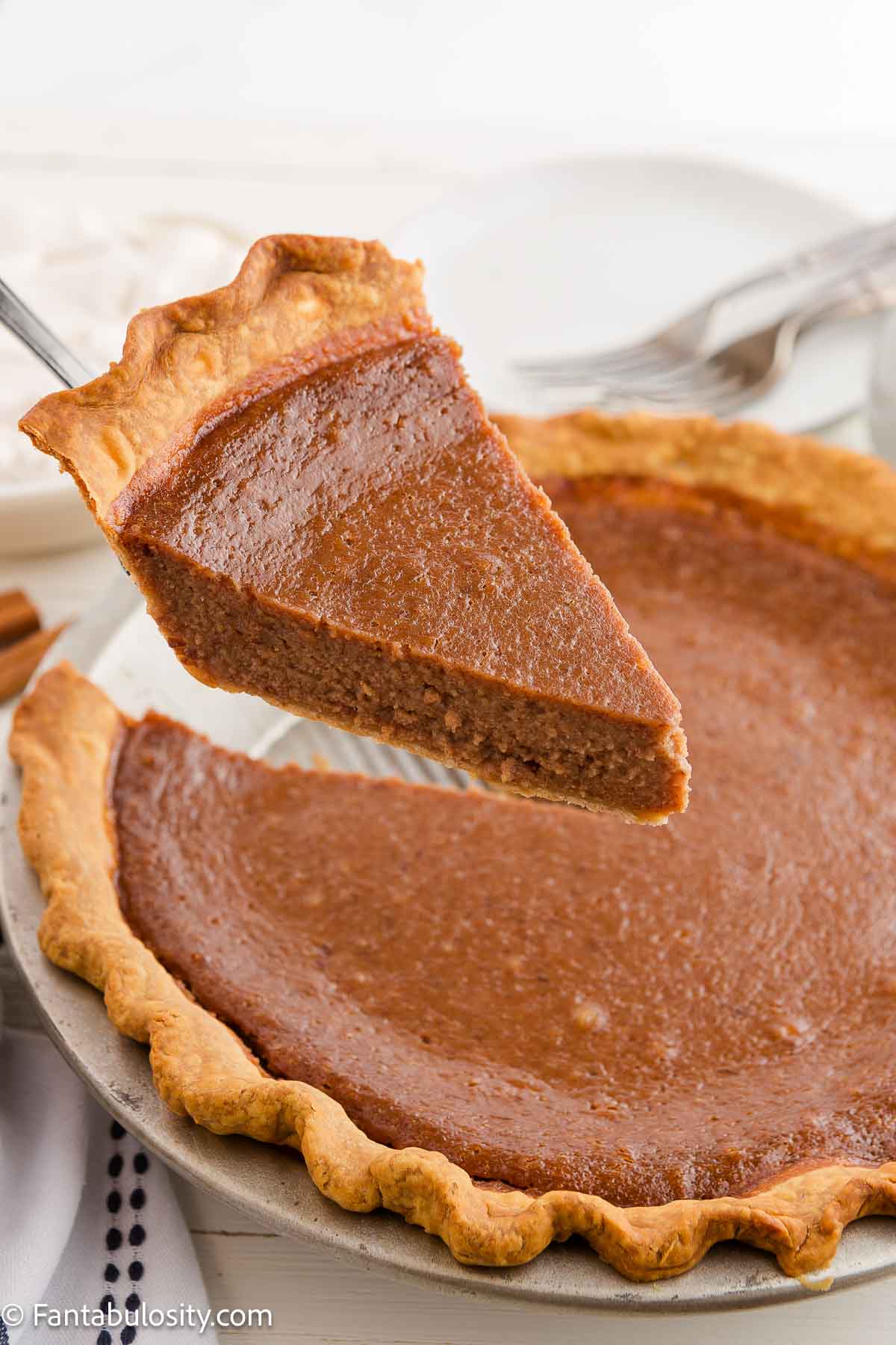 Spatula holding a piece of apple butter pie, up above the rest of the pie.