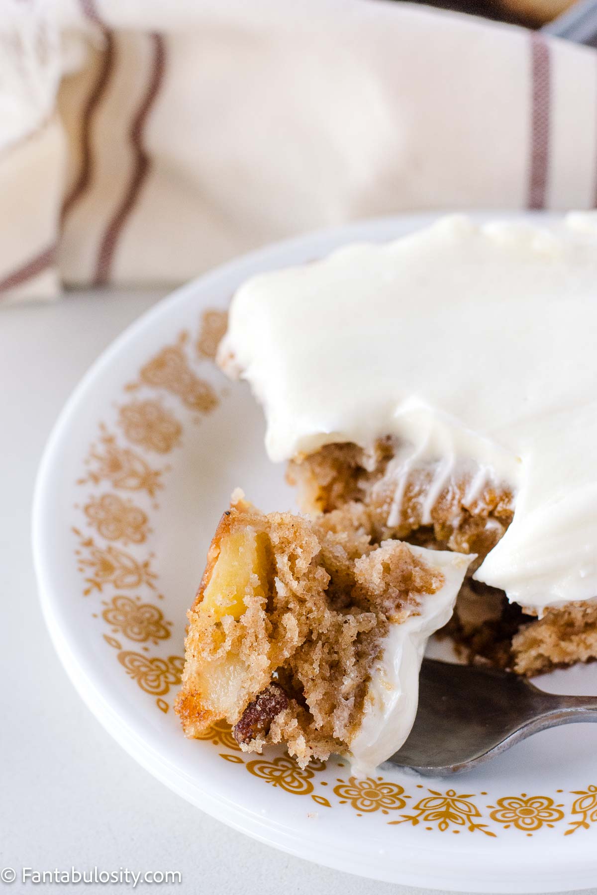 A slice of harvest cake on a vintage dessert plate, with a fork resting next to it, holding a bite of cake.