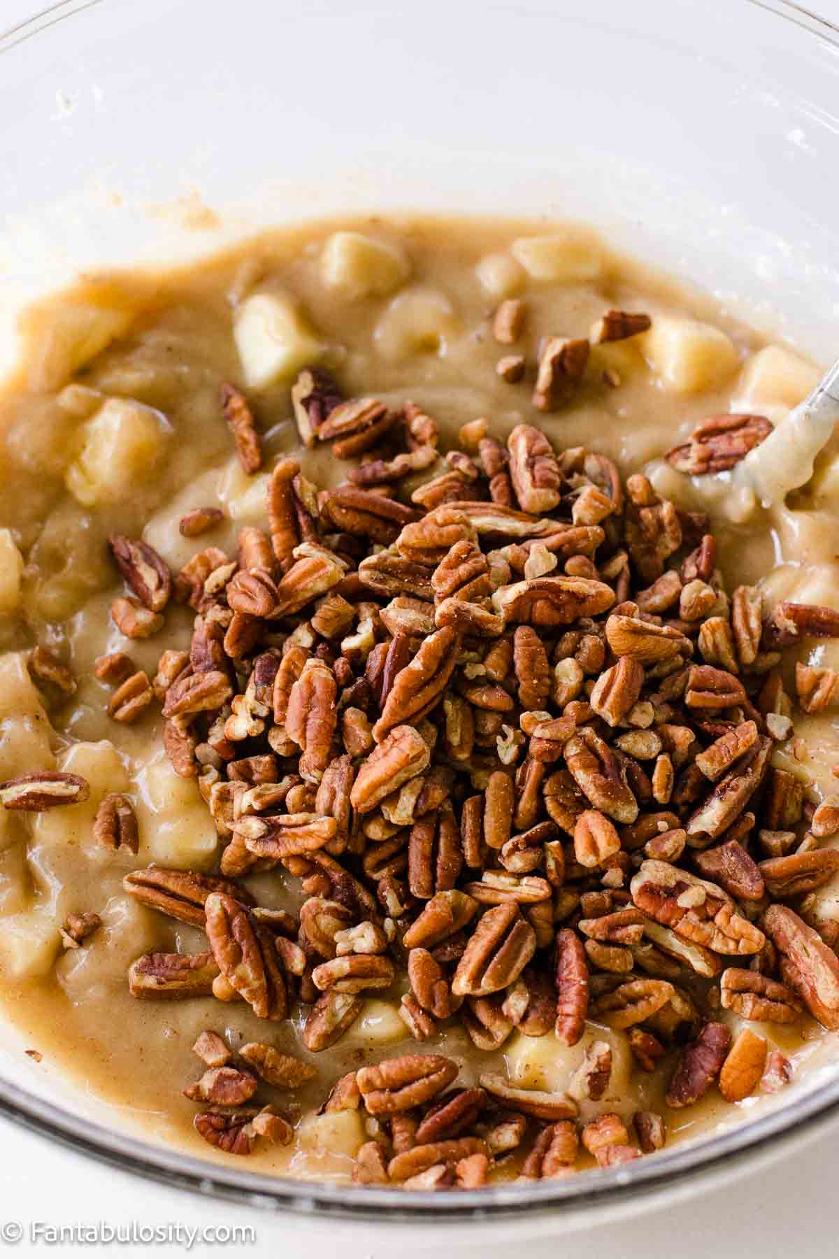 Pecans added to apple mixture in mixing bowl.
