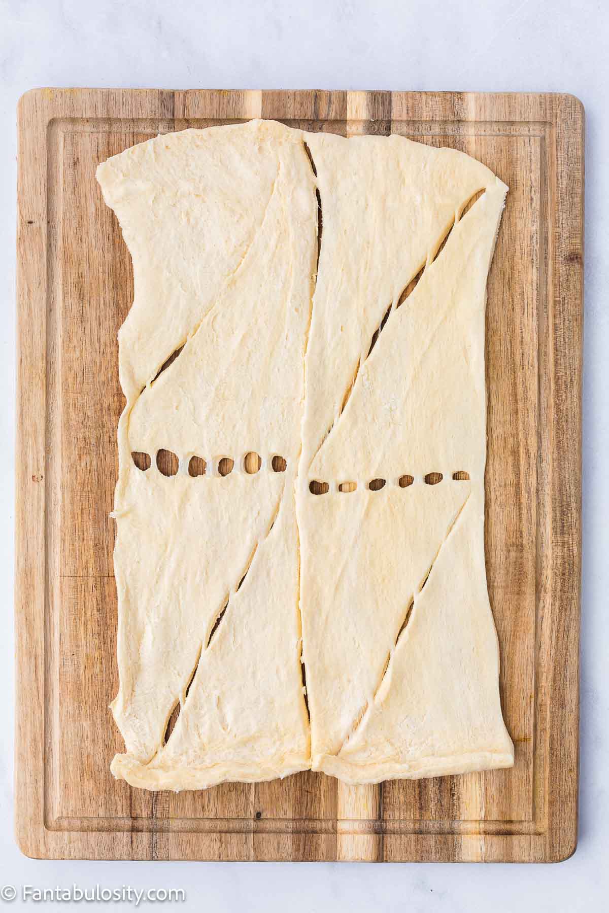 Crescent rolls on wooden cutting board, creating one piece of dough.