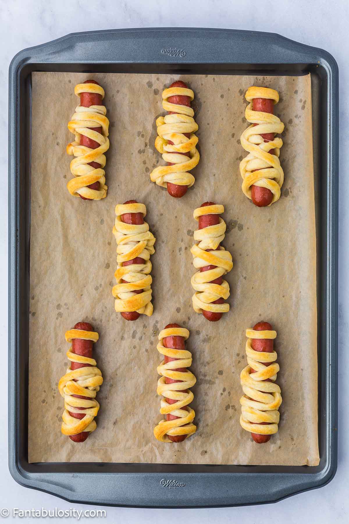 Mummy hot dogs on baking pan.