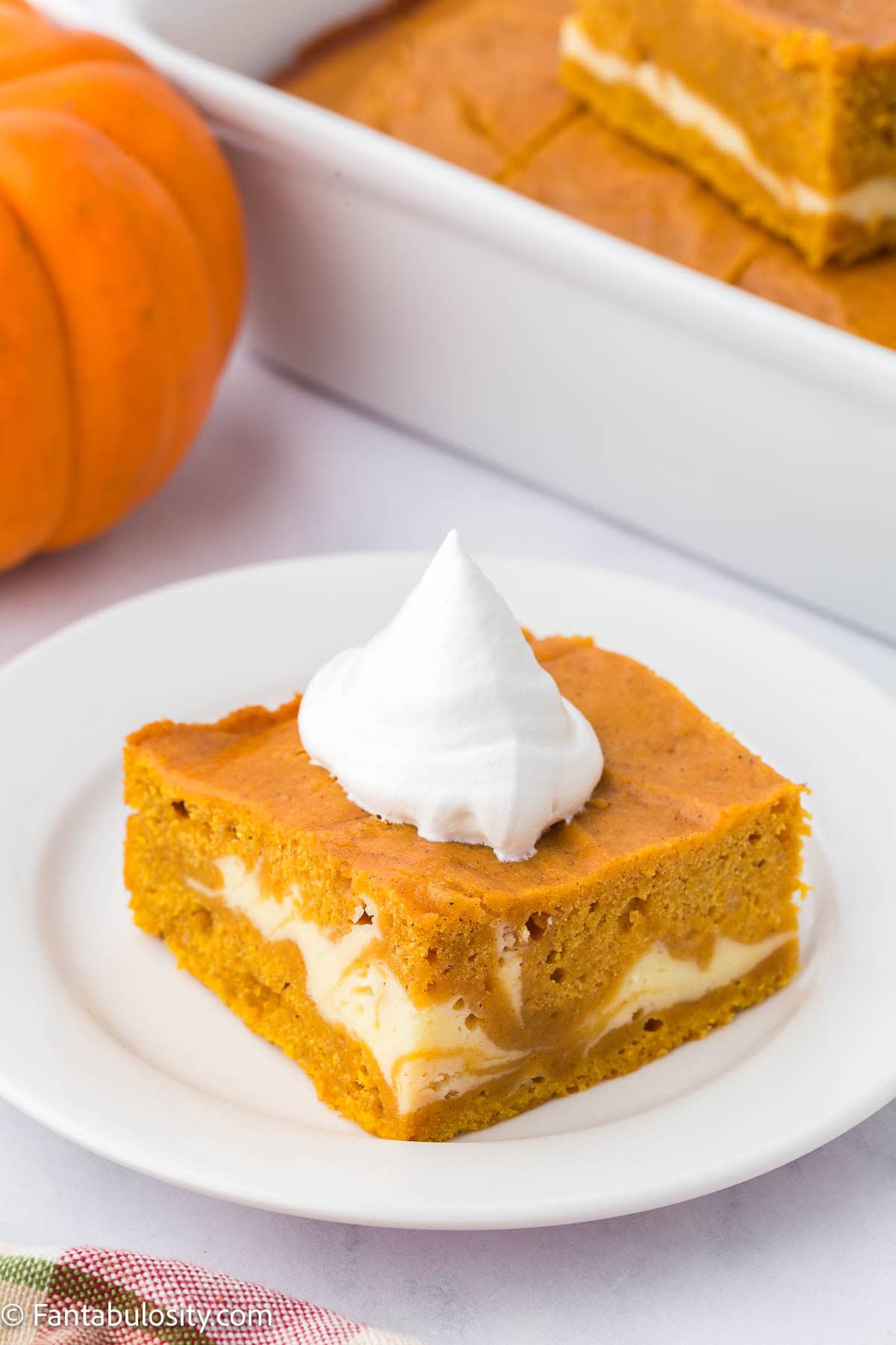 A slice of pumpkin cheesecake sheet cake on round plate.