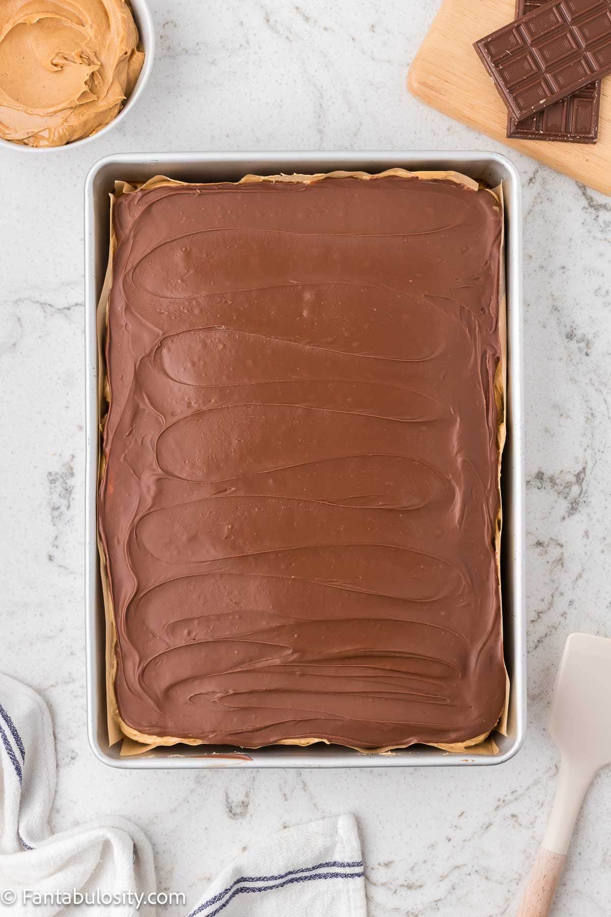 Chocolate topping spread on top of peanut butter frosting on Tandy cake.