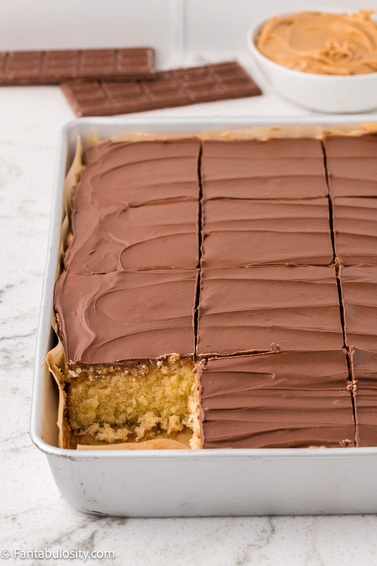 Tandy cake in baking pan, sliced, with a piece removed.
