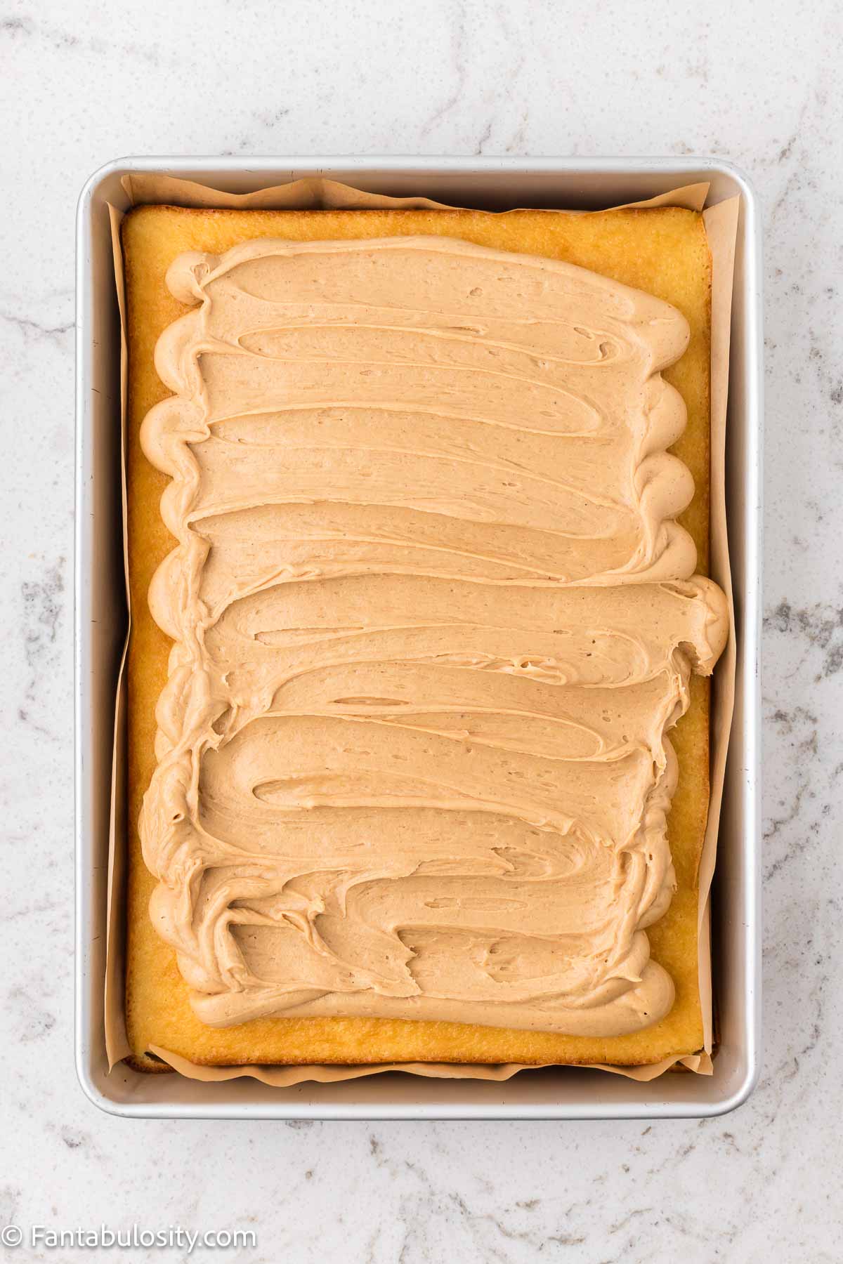 Peanut butter frosting spread over the top of a cooled tandy cake.