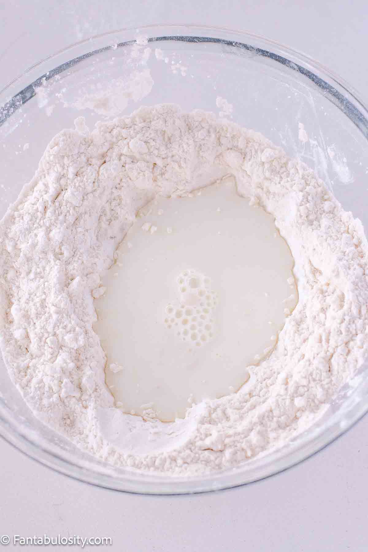 Sifted self-rising flour in mixing bowl, with buttermilk in middle of well.