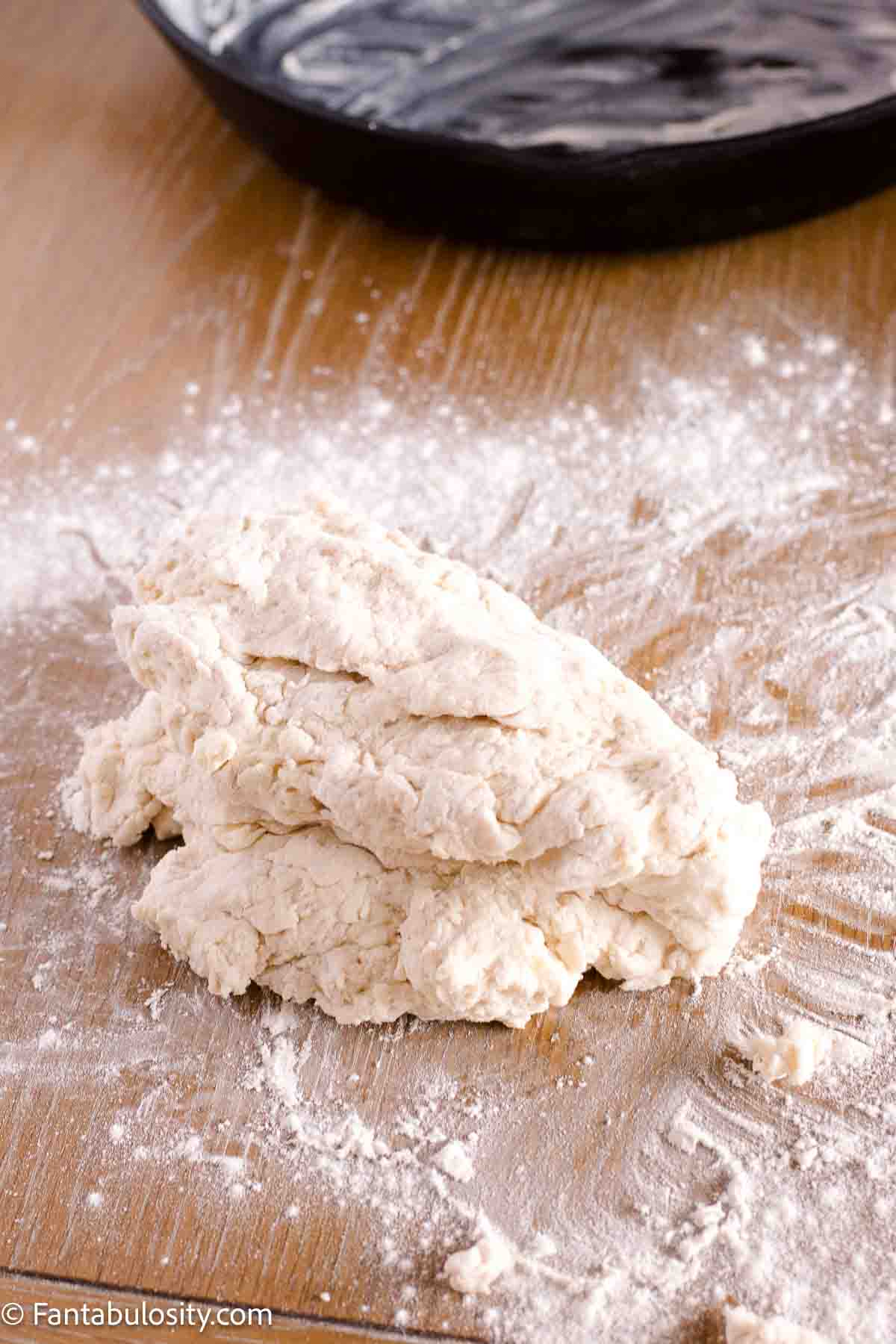 Biscuit dough on table that's covered in flour.