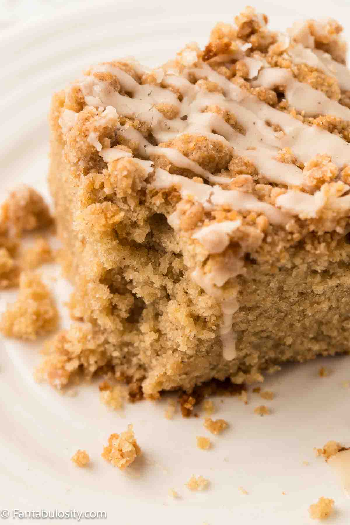 Slice of applesauce crumb cake on plate with a bite taken out.