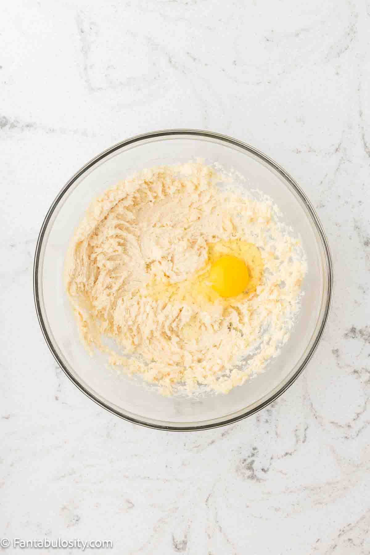Eggs and vanilla added to butter and sugar mixture in mixing bowl.
