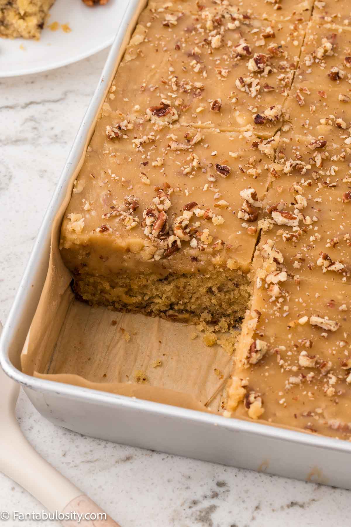 Butter pecan sheet cake, with a slice of cake missing from the pan.