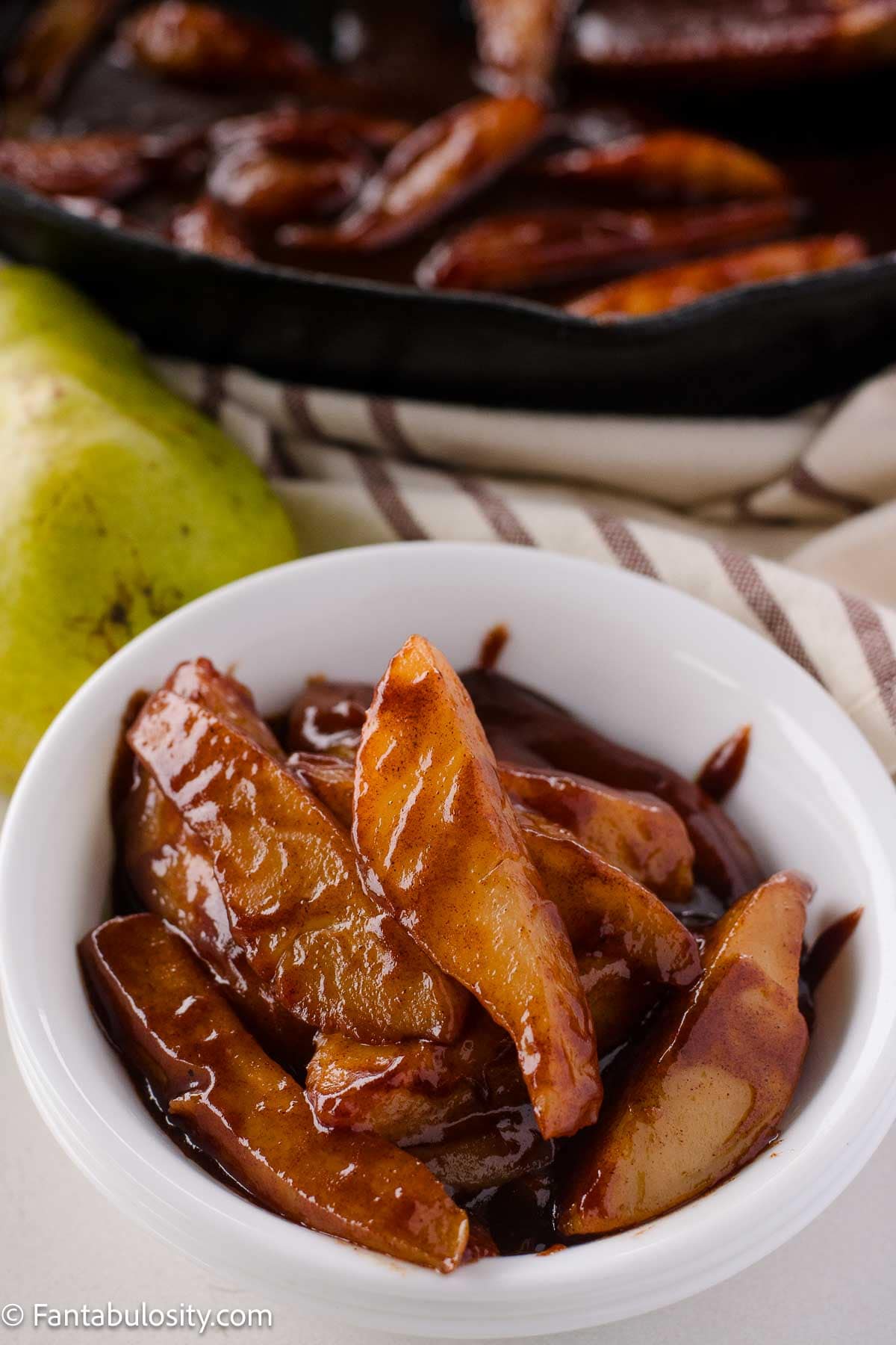 Fried pears in small bowl, sitting next to skillet.
