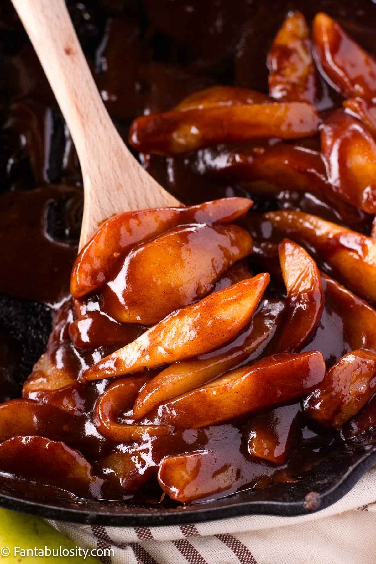 Fried pears sitting in cast iron skillet, on wooden spoon.