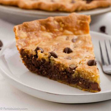 A slice of chocolate chip cookie pie on a plate with a fork.