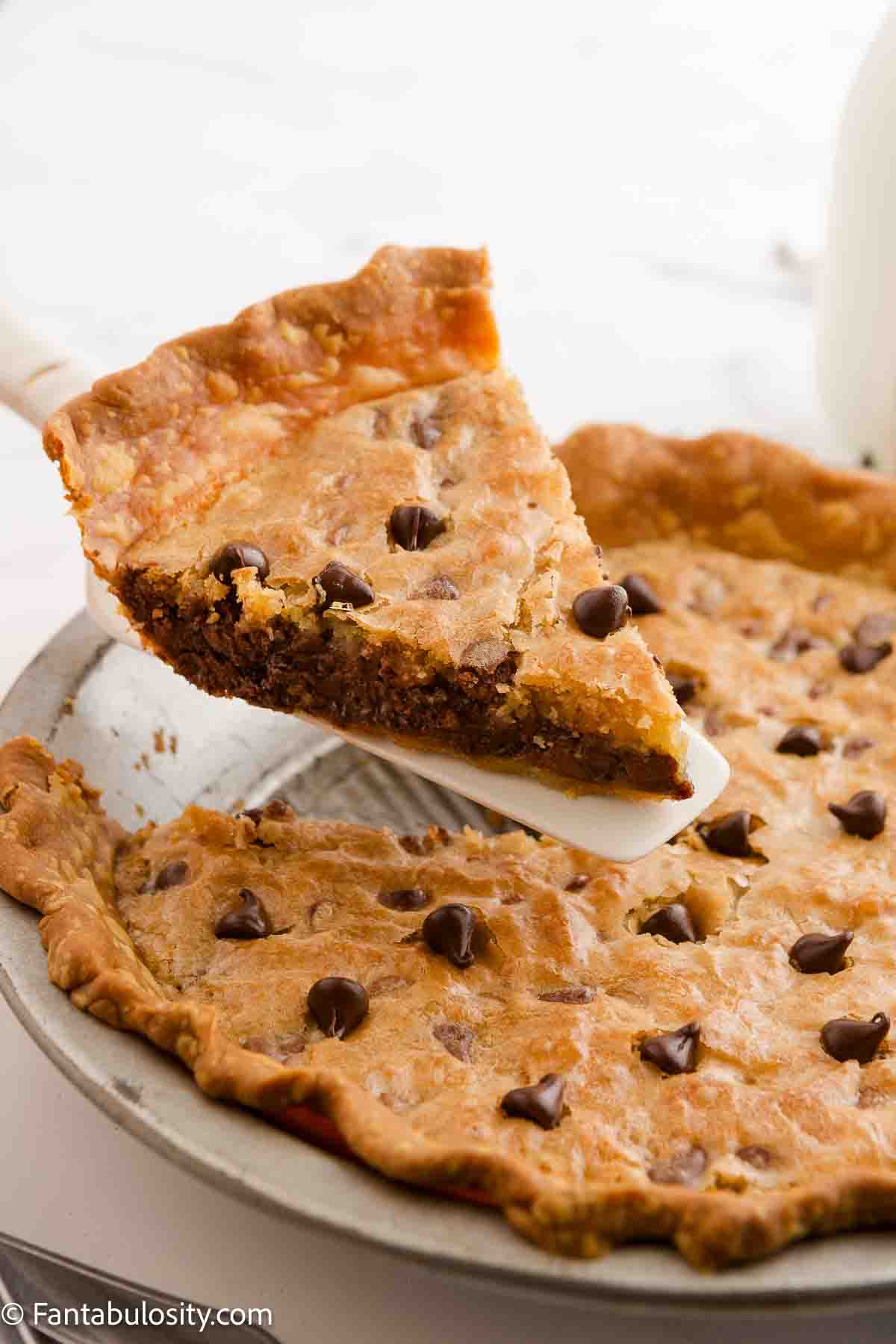 A cake spatula holding a piece of cookie pie above the rest of the pie in the pie plate.