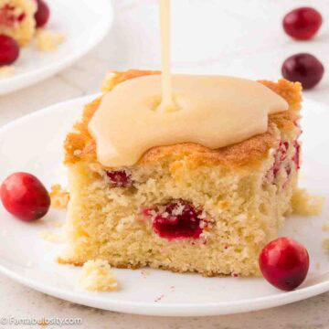 A slice of cranberry cake with butter sauce being poured over the top.
