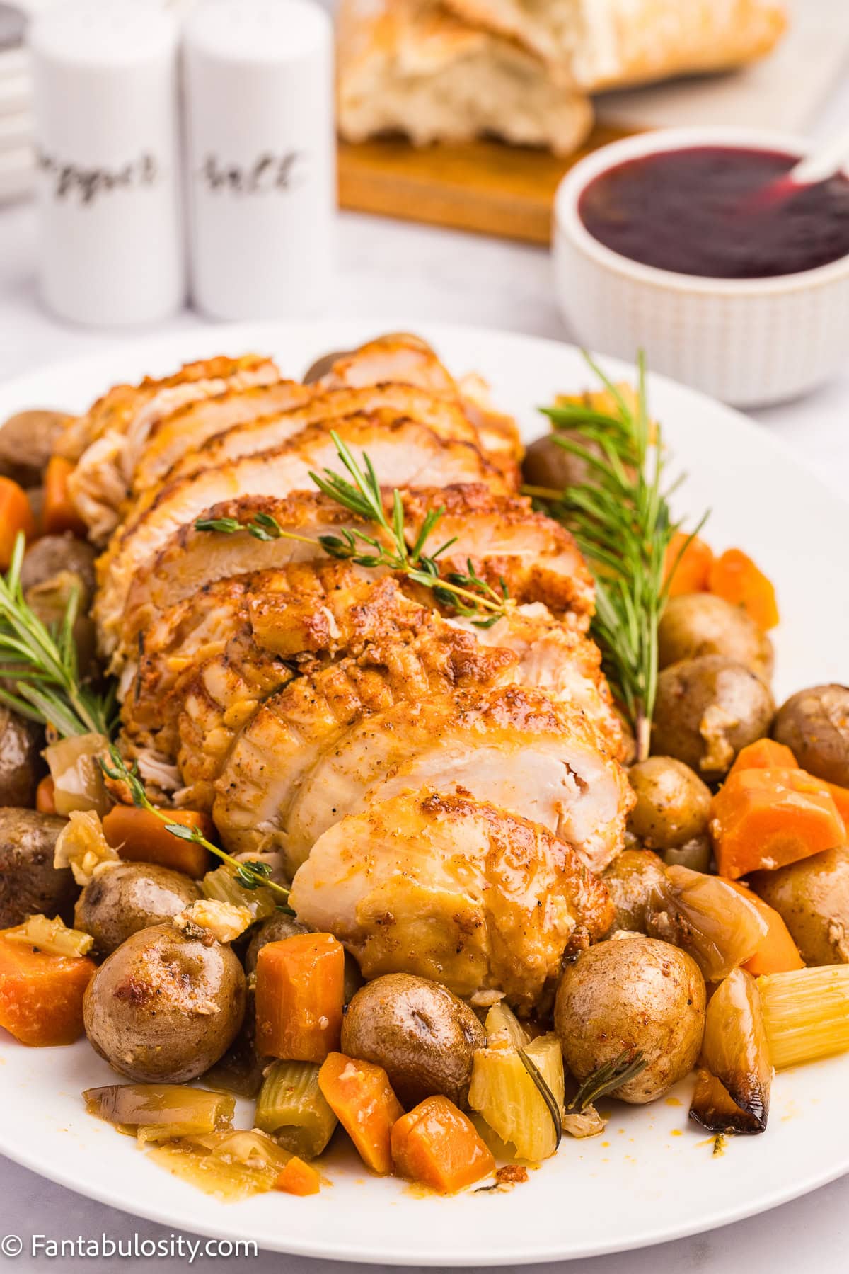Sliced, cooked turkey breast on platter with vegetables.