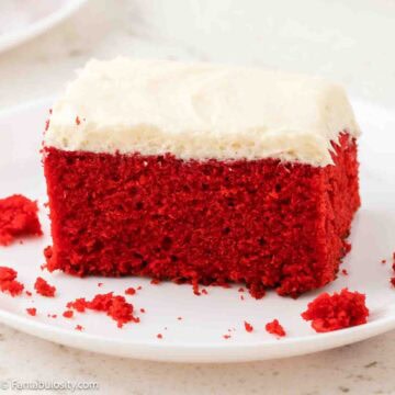 A slice of red velvet sheet cake topped with Ermine frosting, sitting on a plate.