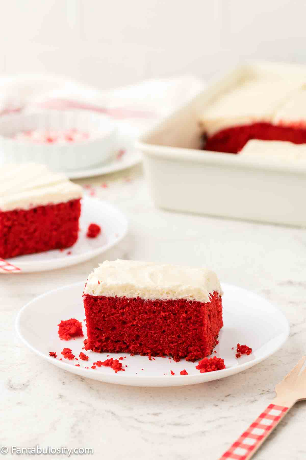 A slice of red velvet cake, topped with Ermine frosting on a plate.