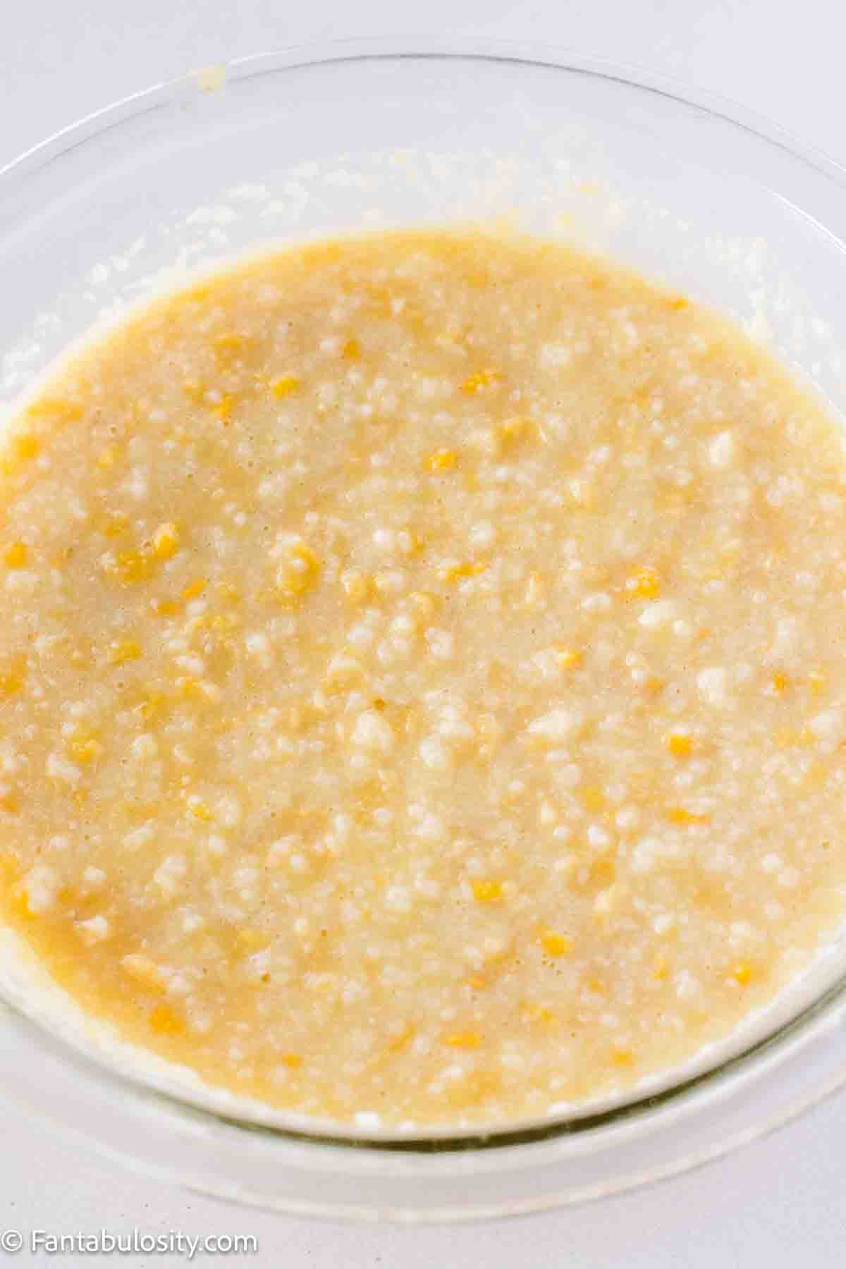 Creamed corn, egg, honey, and milk in a glass mixing bowl.
