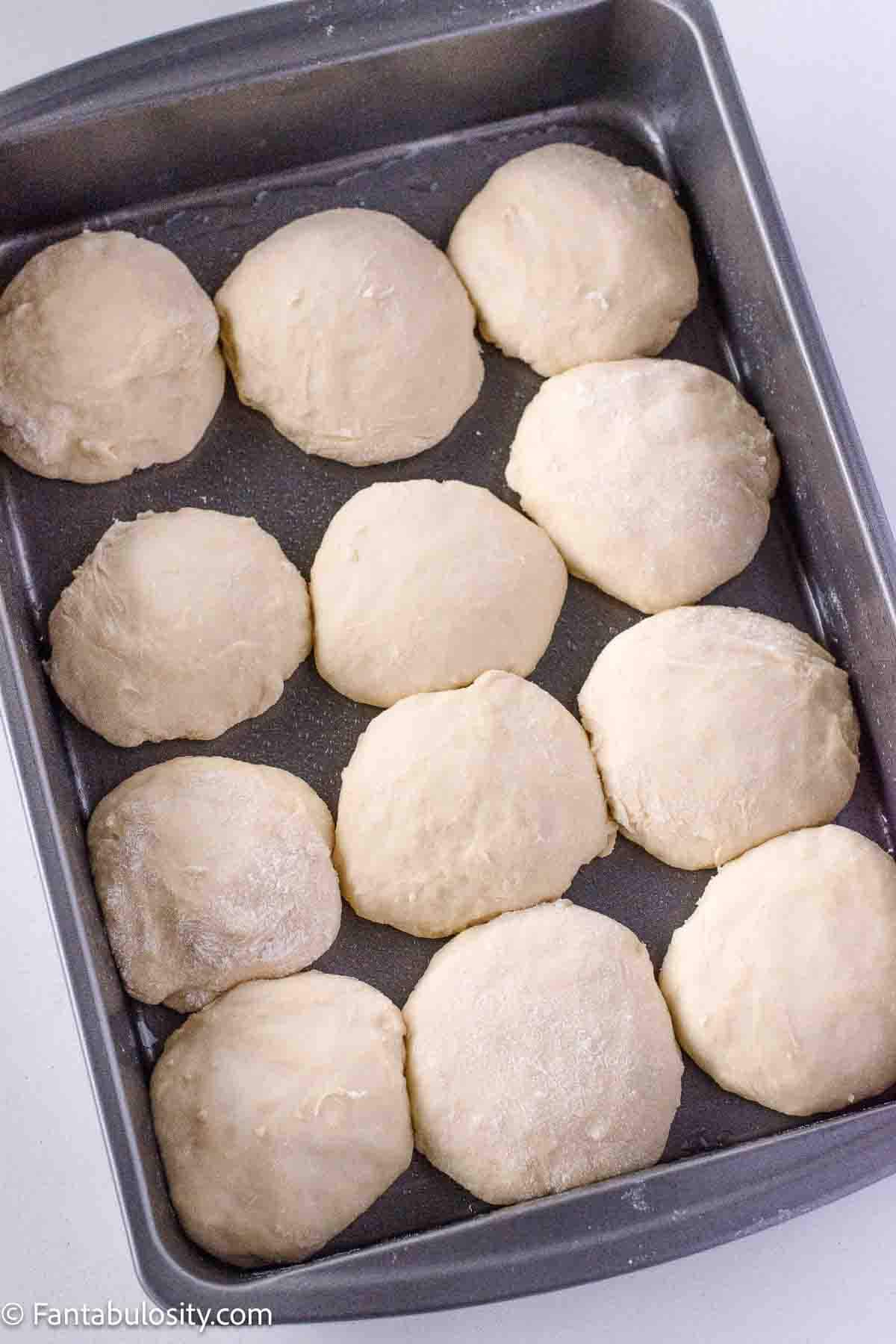 Yeast rolls in baking pan, rising for baking.