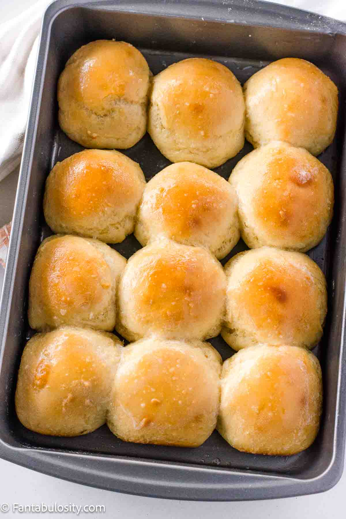 Baked, homemade yeast rolls in an aluminum baking pan.
