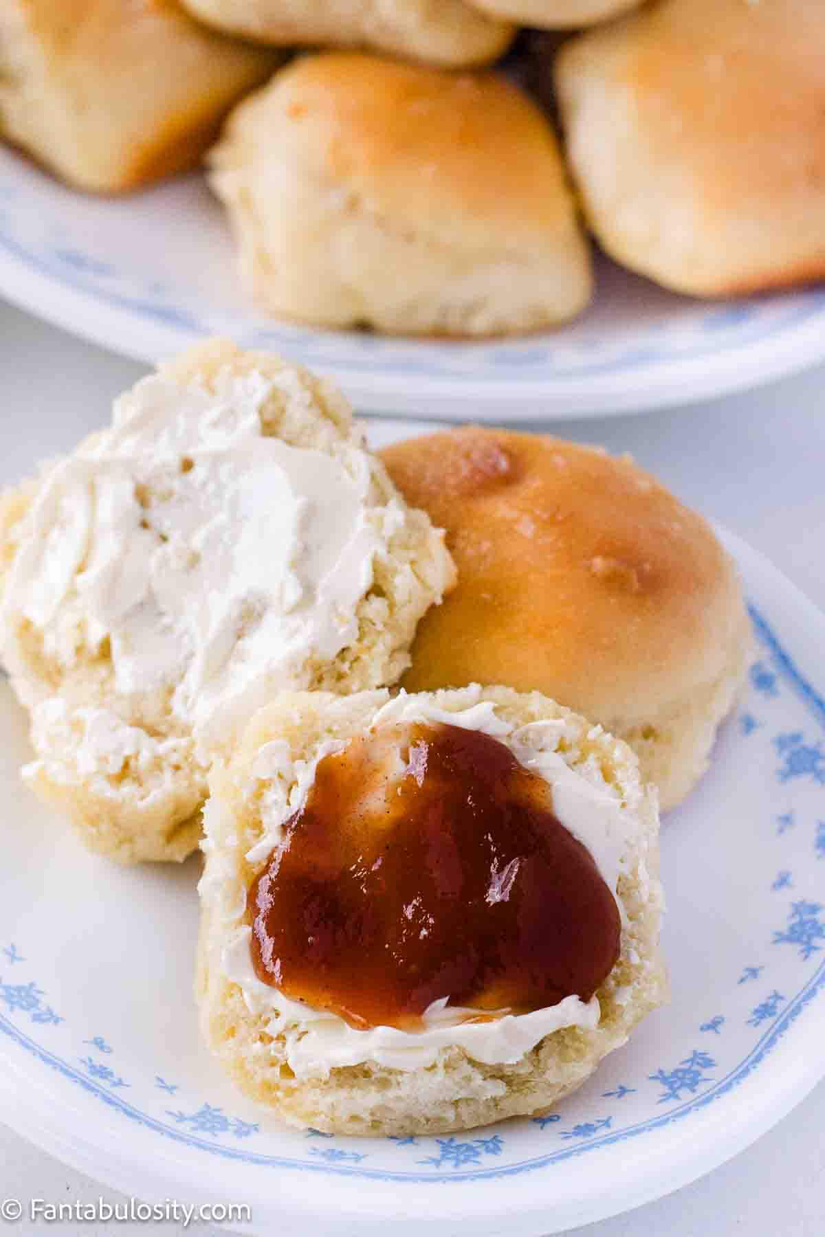 Yeast roll, sliced in half, and topped with butter and apple butter, sitting on vintage plate.
