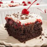 A slice of black forest poke cake on a plate.