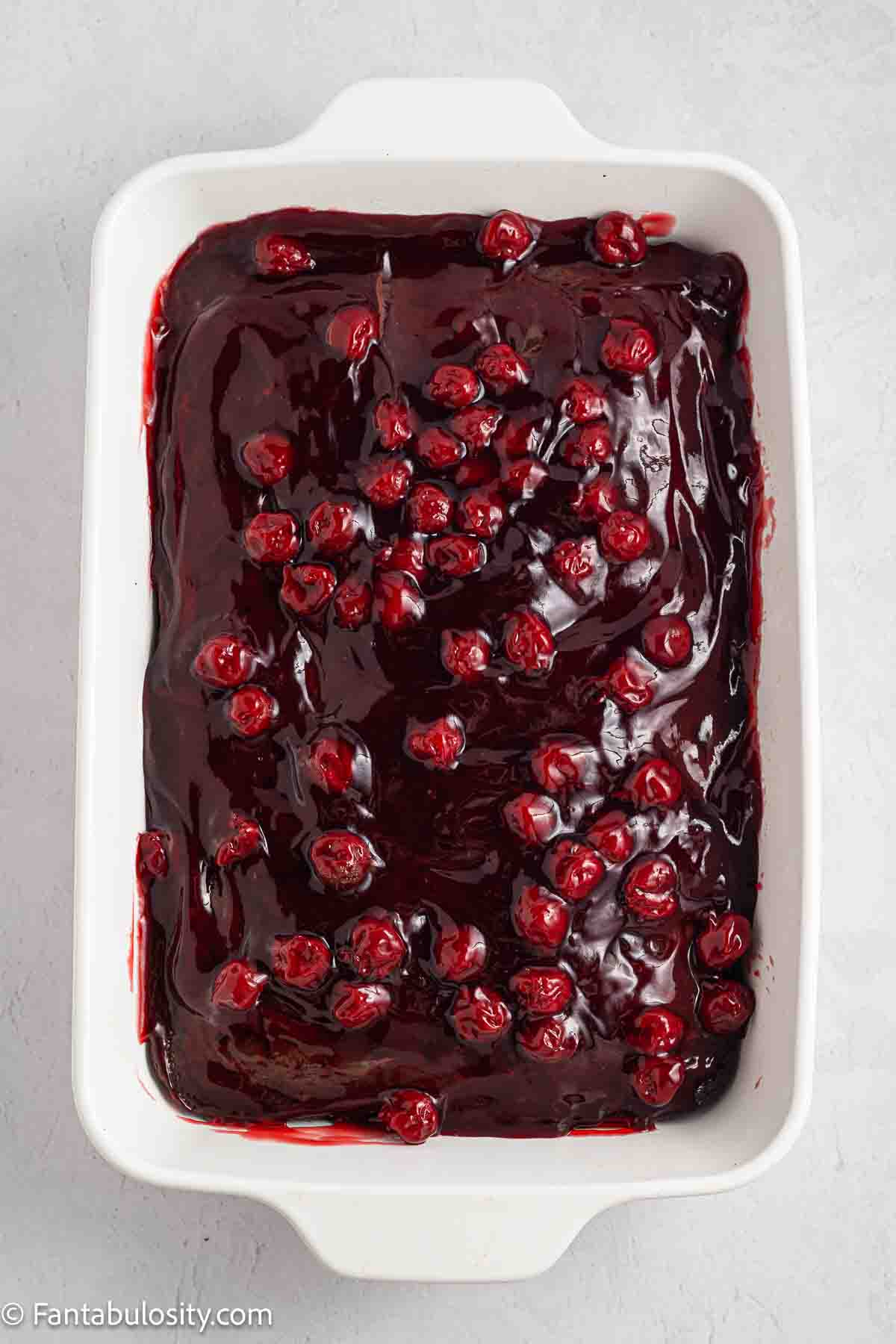 Cherry pie filling poured over the top of a baked chocolate cake.