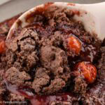 Cherry chocolate dump cake being spooned out of baking dish.