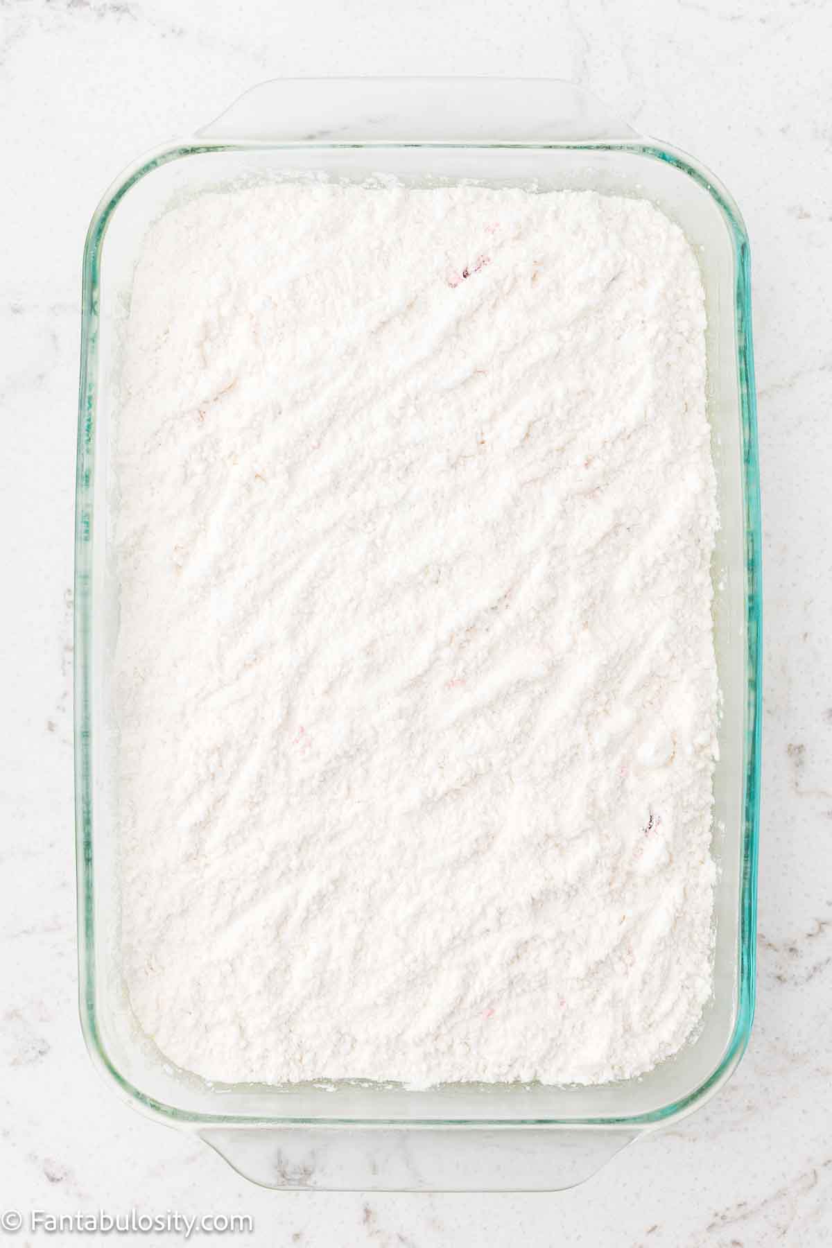 Yellow cake mix sprinkled on top of the cherry pie filling.