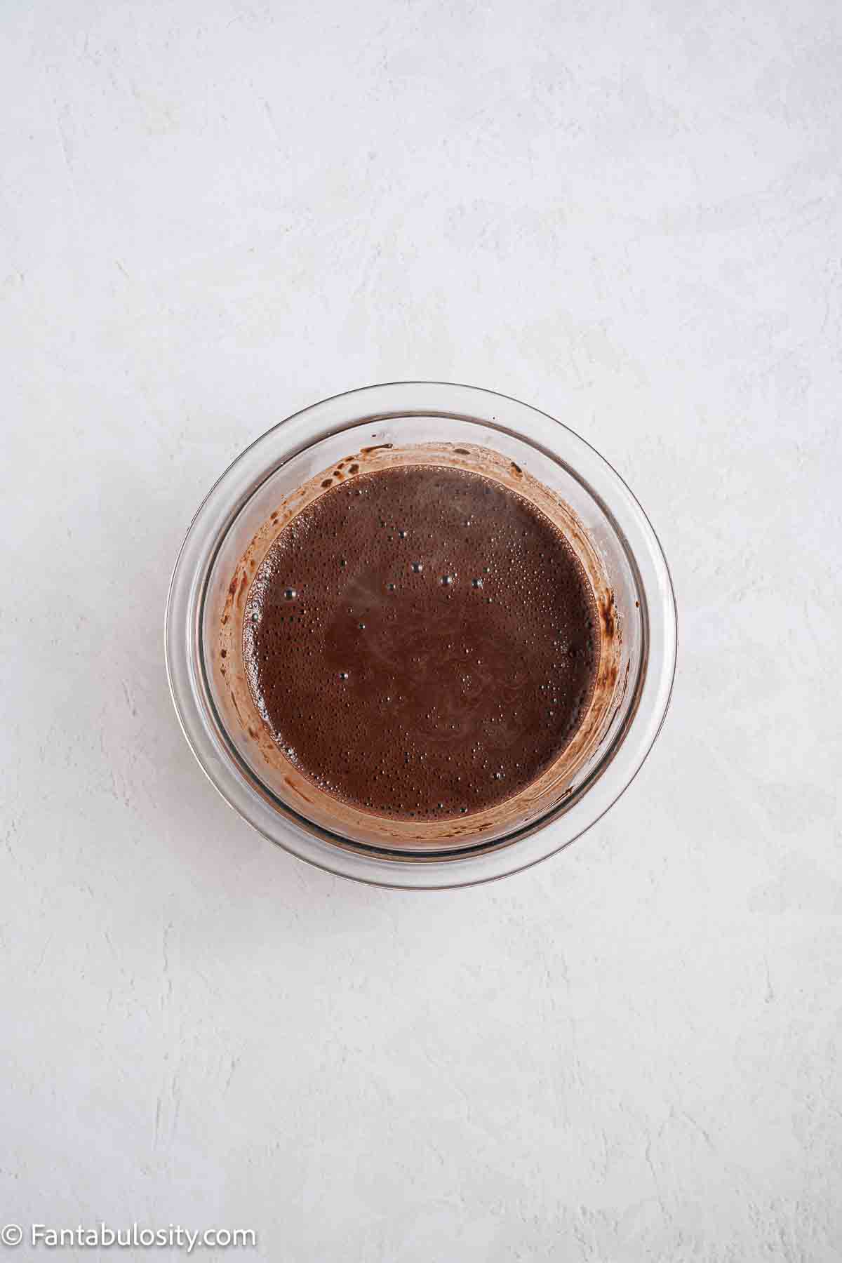 Cocoa and hot water mixed together in mixing bowl.