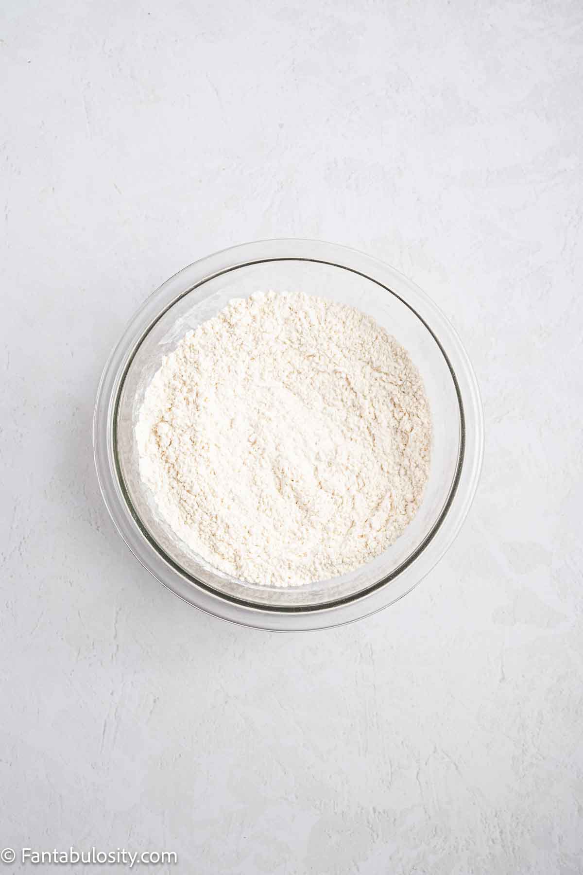 Flour, baking soda, baking powder, and salt in a mixing bowl.