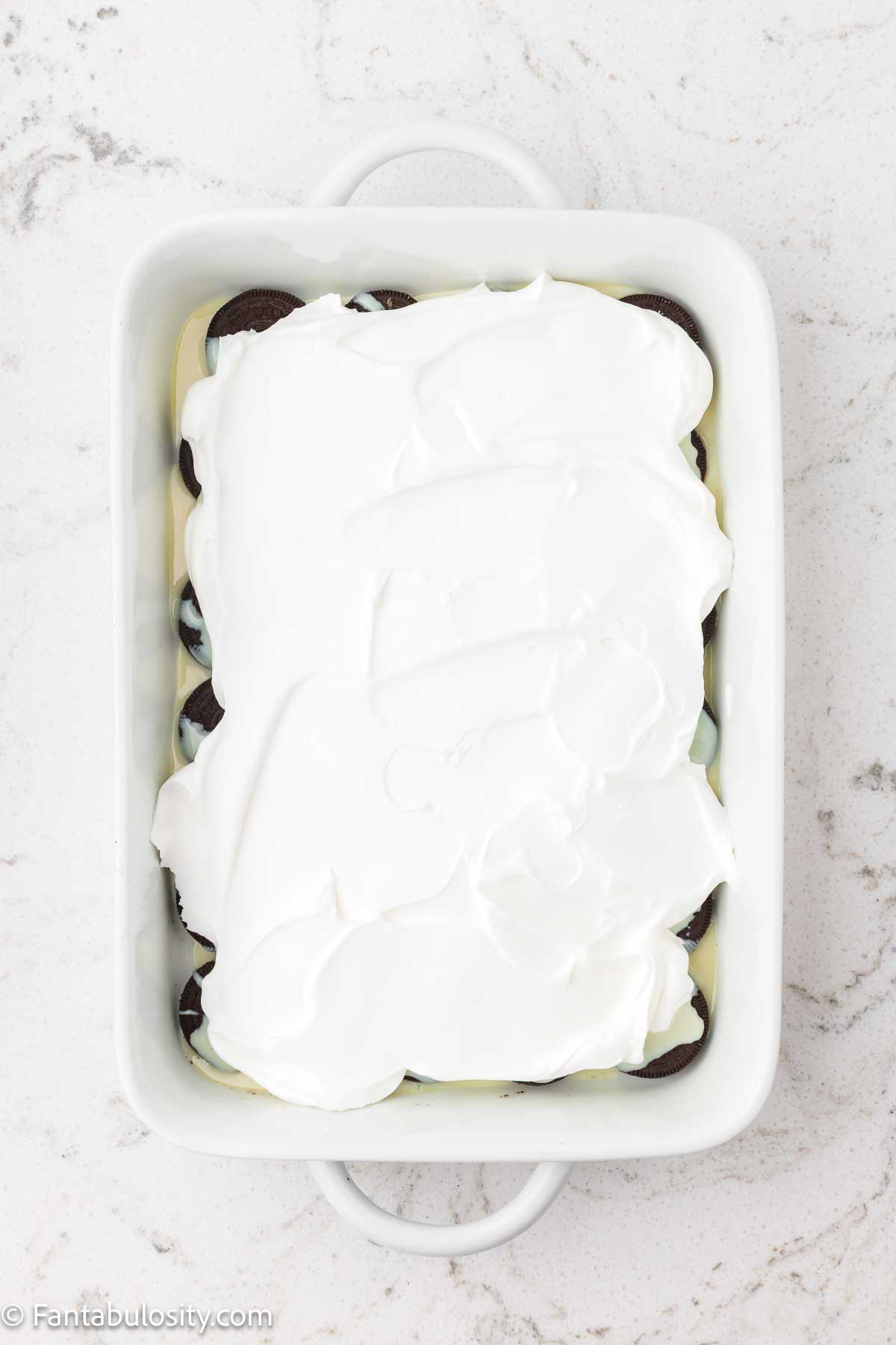 Cool Whip spread over the top of the sweetened condensed milk in a baking dish.