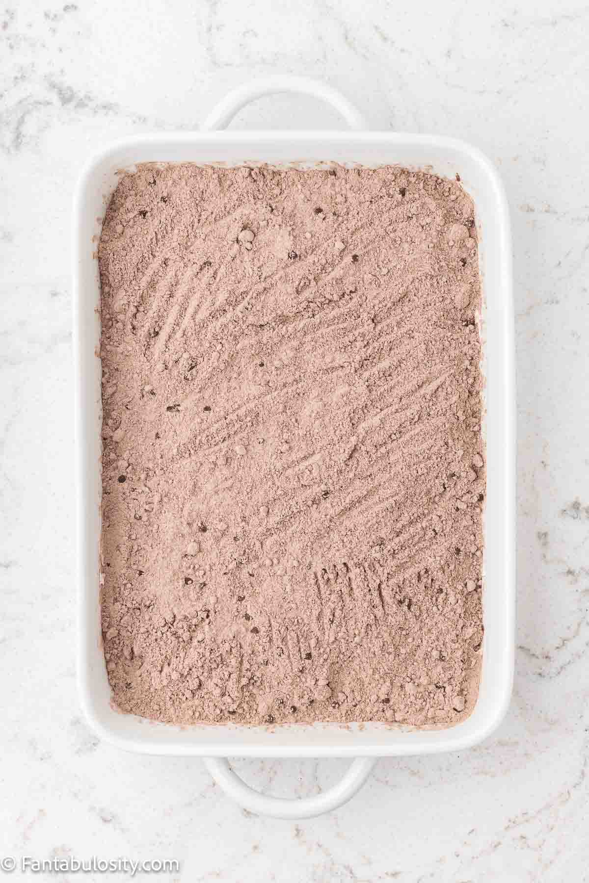 Chocolate cake mix sprinkled over the top of the Cool Whip in 9x13 baking dish.