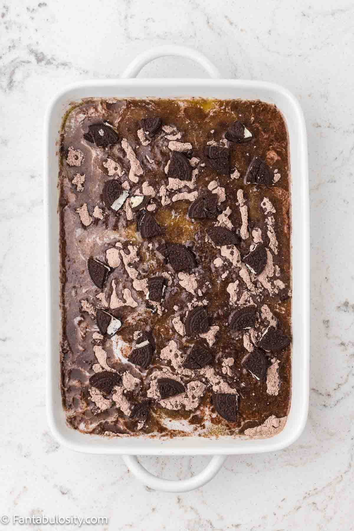 Pieces of Oreo cookies sprinkled on top of chocolate Oreo dump cake in 9x13 baking dish.