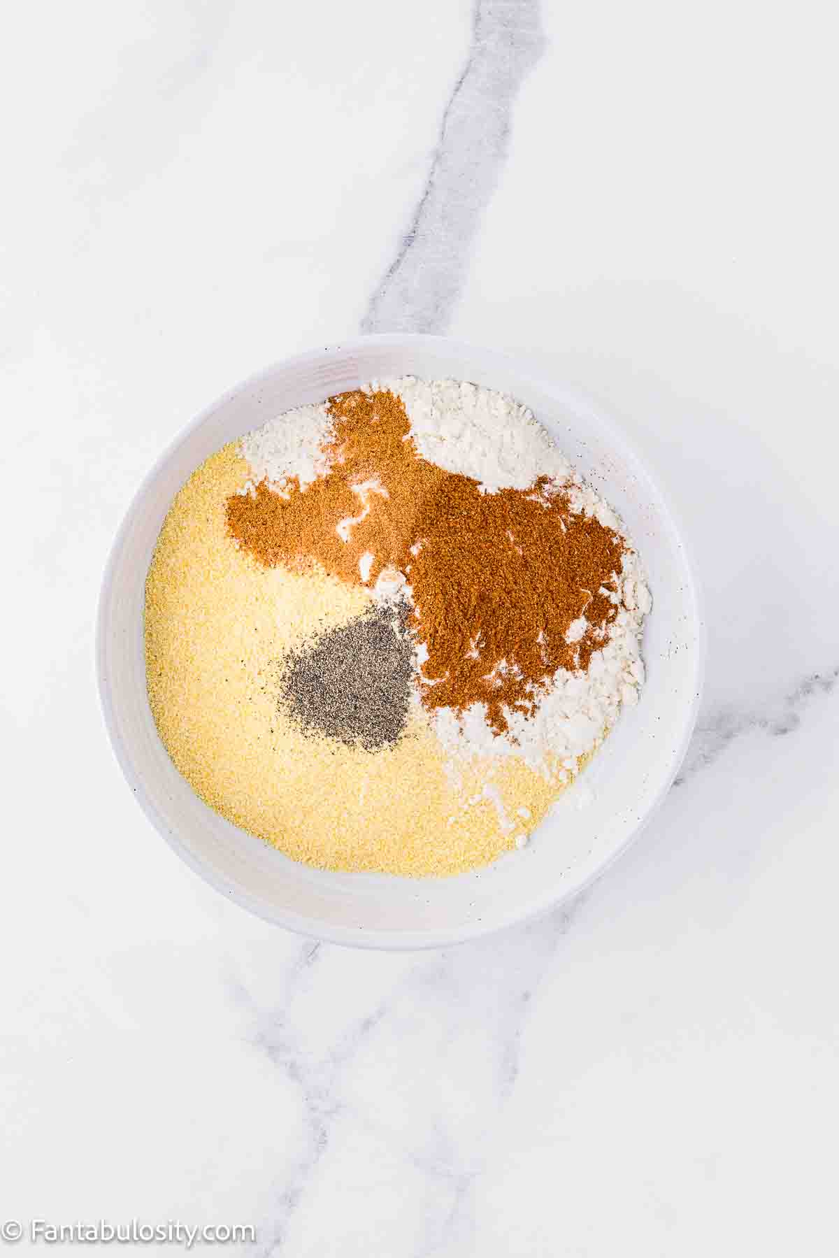 Cornmeal, flour, seasoned salt, Old Bay seasoning mixed together in shallow dish.