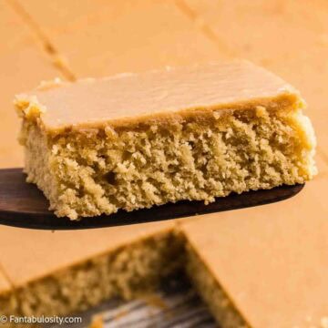 A slice of caramel cake with caramel frosting on a spatula.