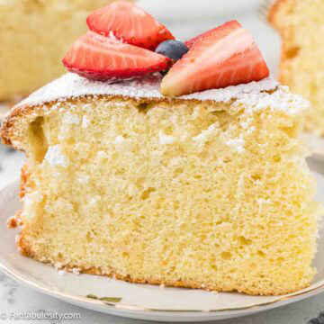 A slice of cloud cake, topped with strawberries, sitting on round plate.
