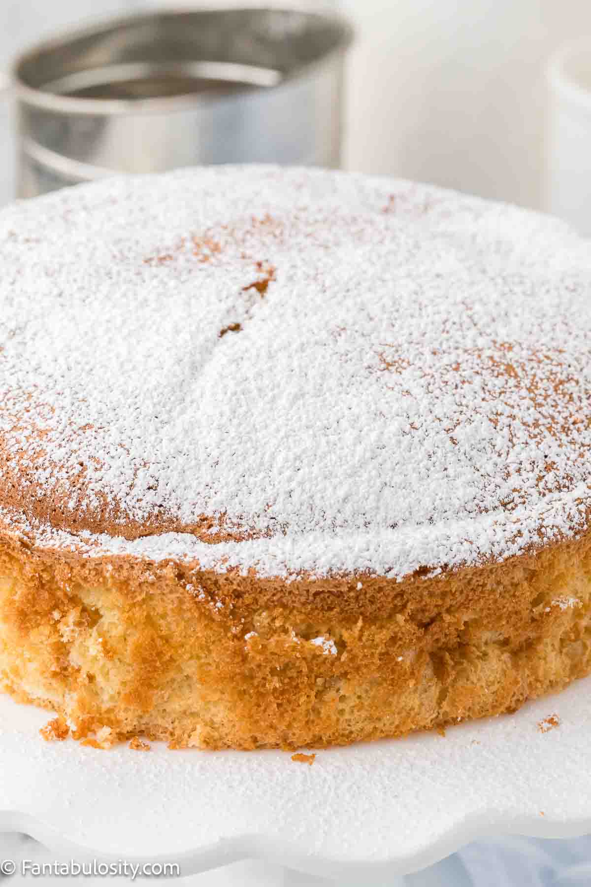 Cloud cake on cake stand with powdered sugar sprinkled on top.