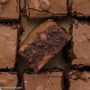 Condensed milk brownies on parchment paper with middle brownie turned up on it's side.