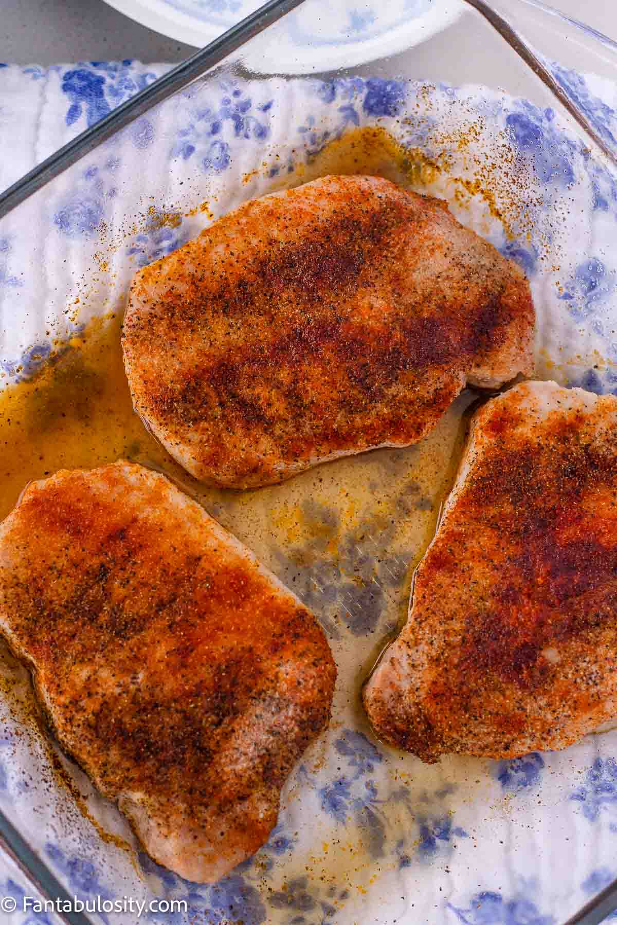 Three baked boneless pork chops in a glass baking dish.