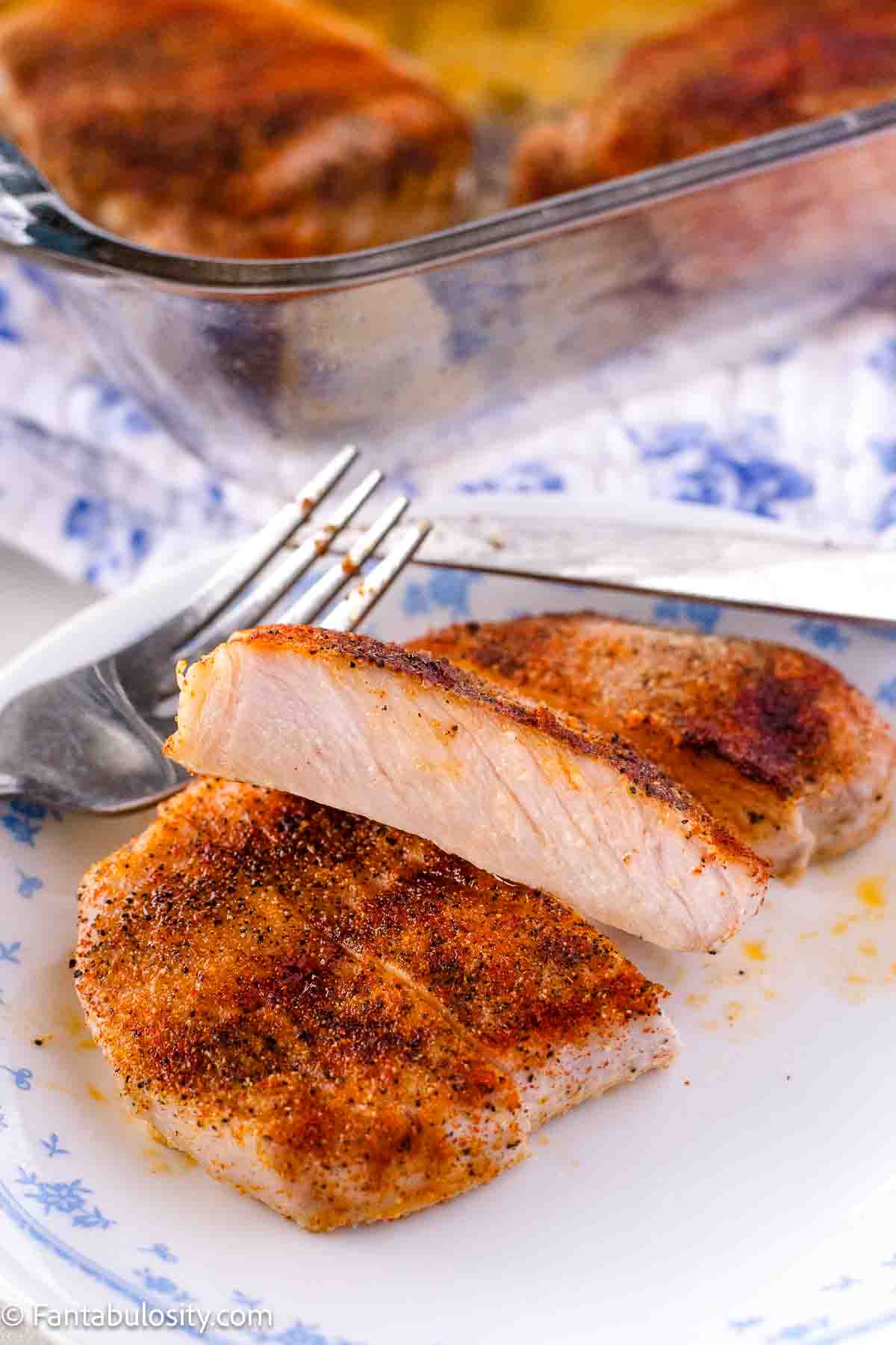 Baked boneless pork chop, sliced to show middle, sitting on a plate.