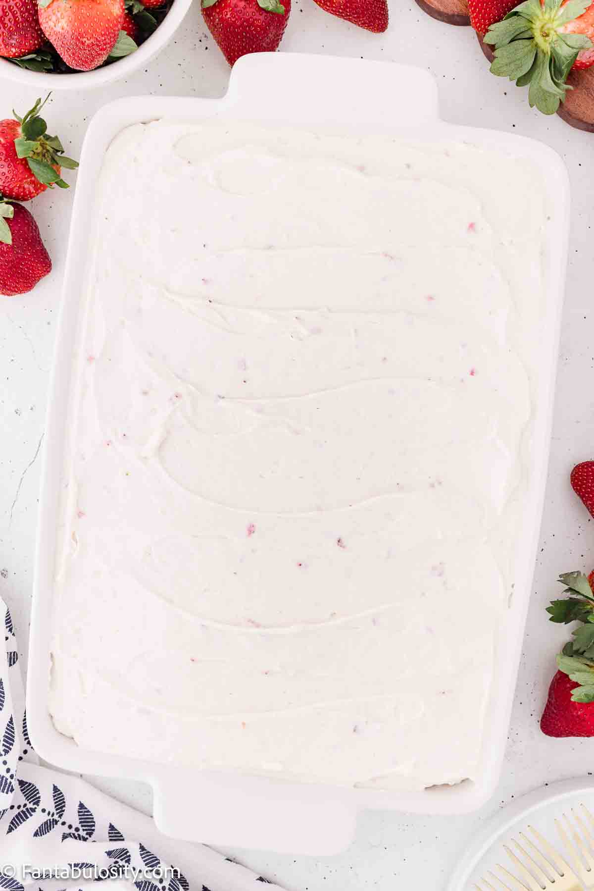 Strawberry cream cheese frosting spread on top of strawberry jello cake.