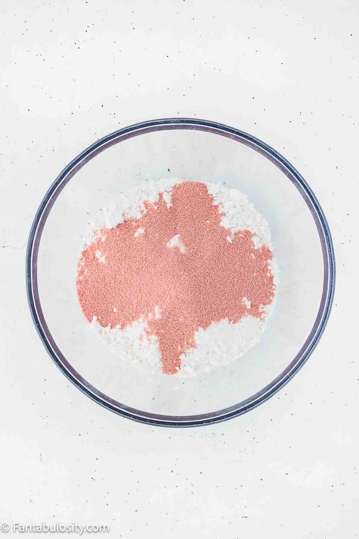 White cake mix and strawberry gelatin powder mixed together in mixing bowl.
